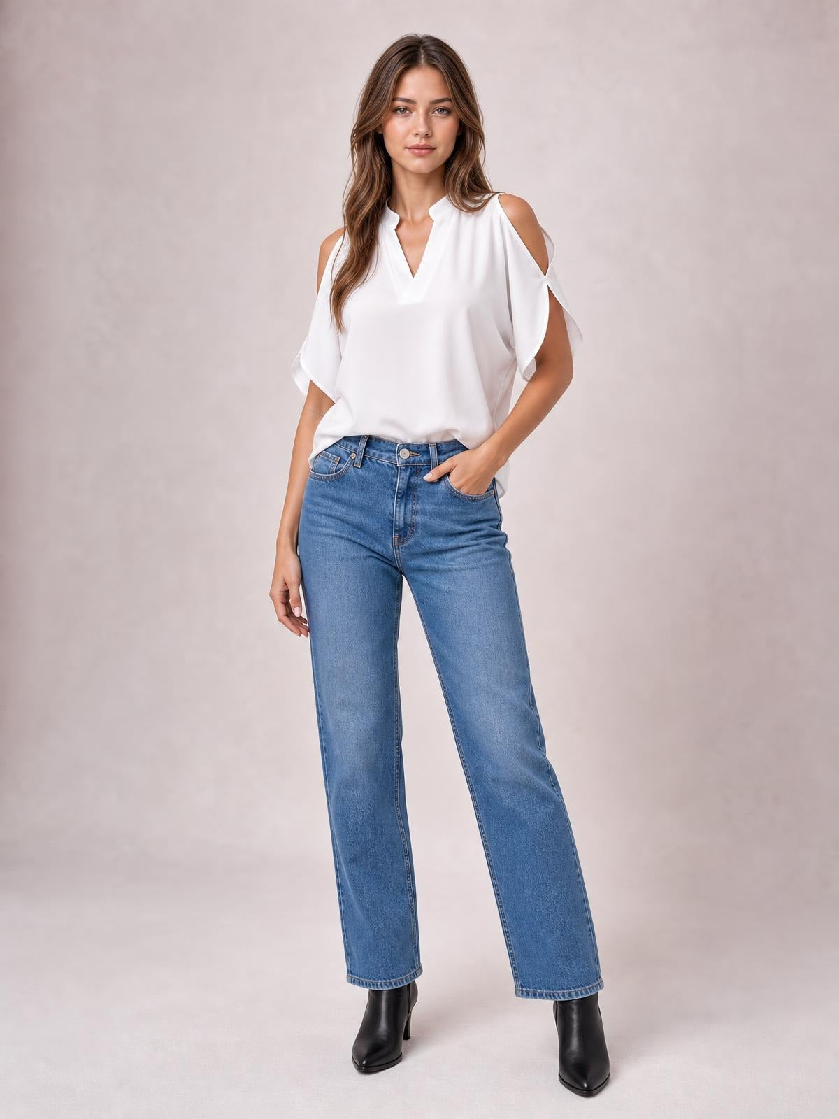 Model wears a white notched cold shoulder blouse with half sleeves, a relaxed straight silhouette, and draped construction, posing with one hand in her jeans pocket.