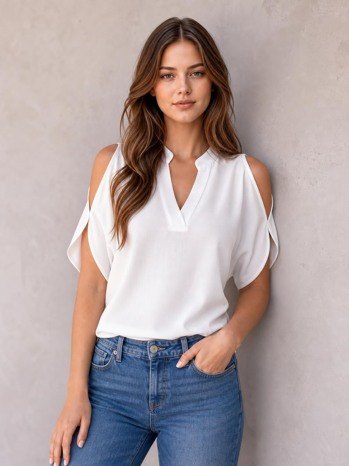 A model stands in a white notched cold shoulder blouse with flowing half sleeves, shoulder cutouts, a relaxed silhouette, and an opaque finish.