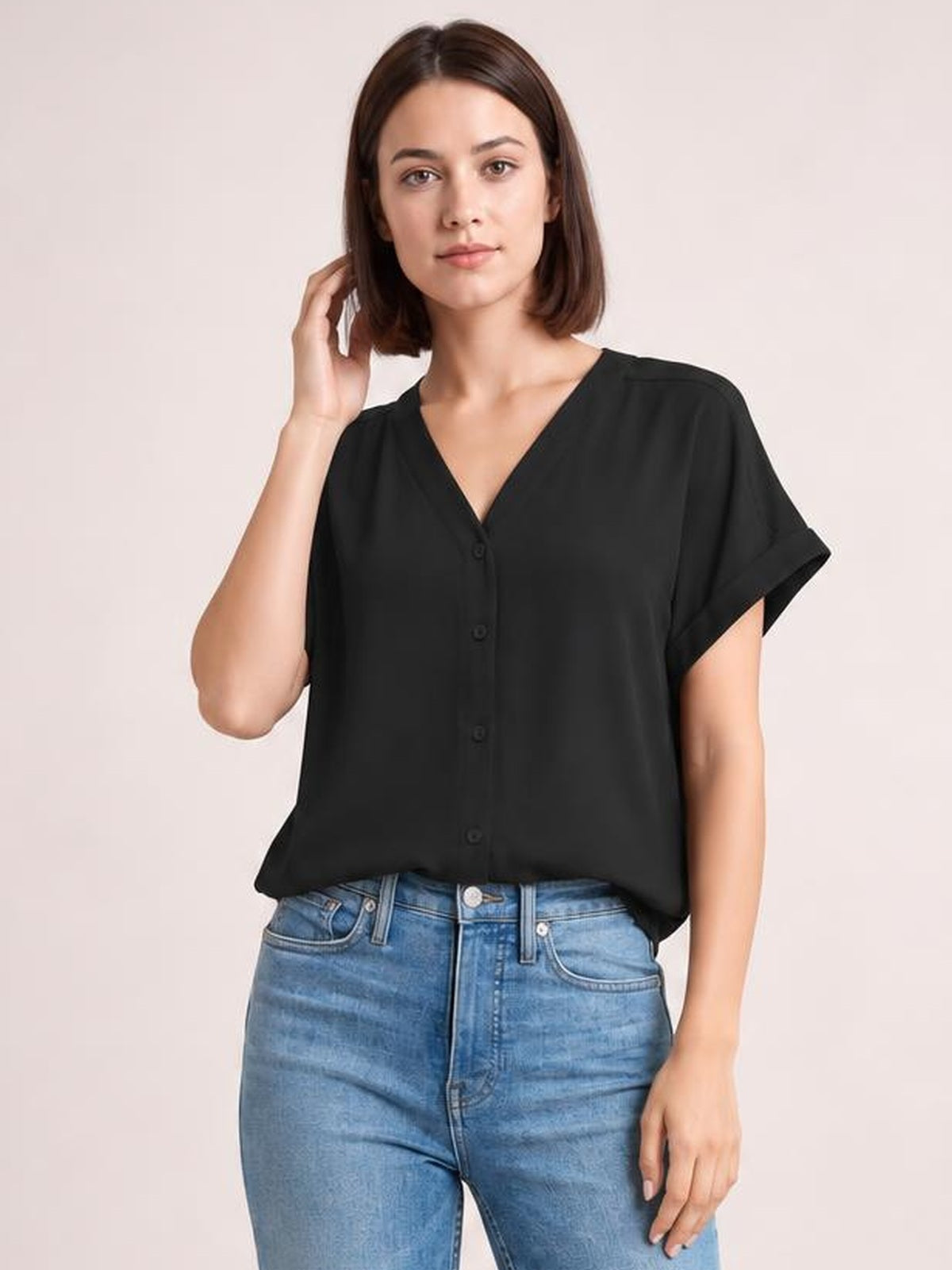 A model poses in a solid black shirt with a notched neckline, button front, short cuffed sleeves, and a relaxed regular-length silhouette.