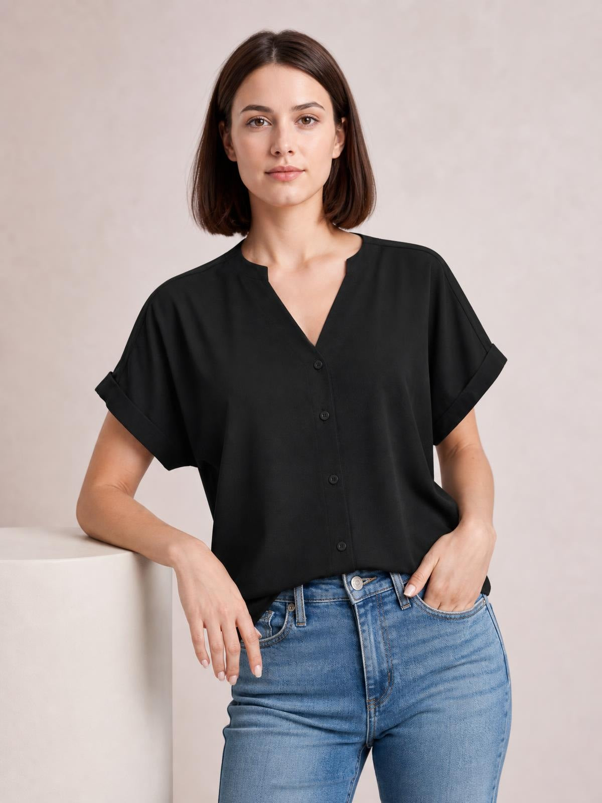 A model wears a solid black casual shirt with a notched neckline, button front, short cuffed sleeves, and a relaxed regular-length silhouette.