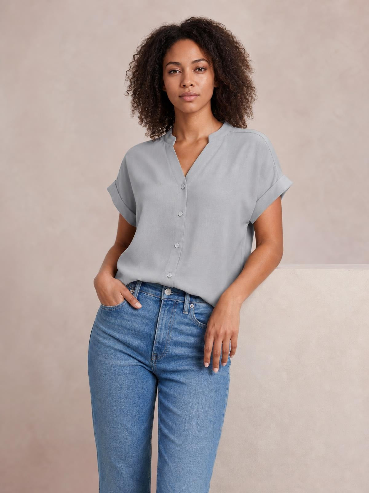 Model wears a solid light gray shirt with a notched neck, button front, cuffed short sleeves, and a relaxed regular-length silhouette.