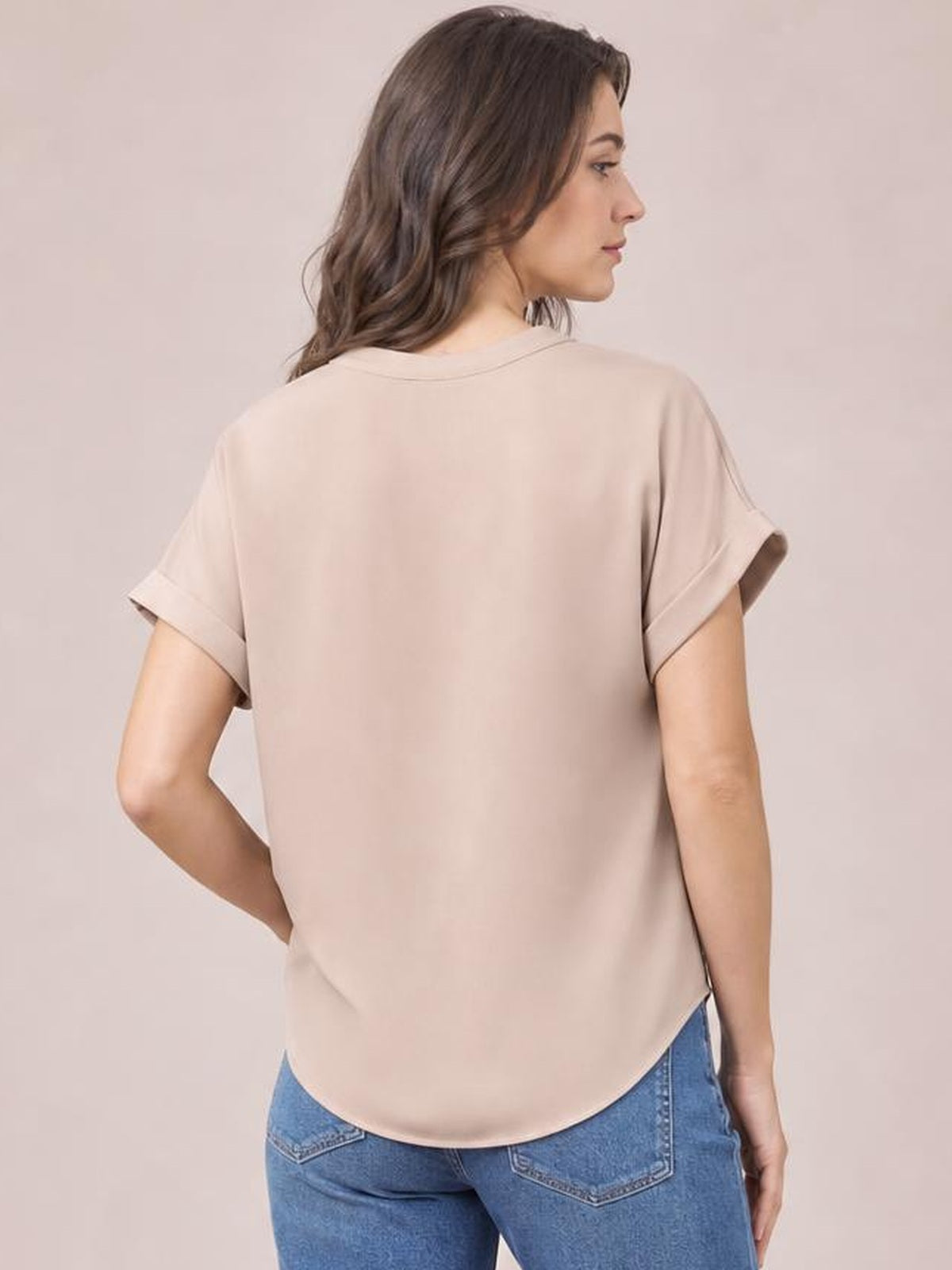 Model shown from behind wearing a solid beige casual shirt with short cuffed sleeves, a relaxed regular-length silhouette, and a rounded hem.