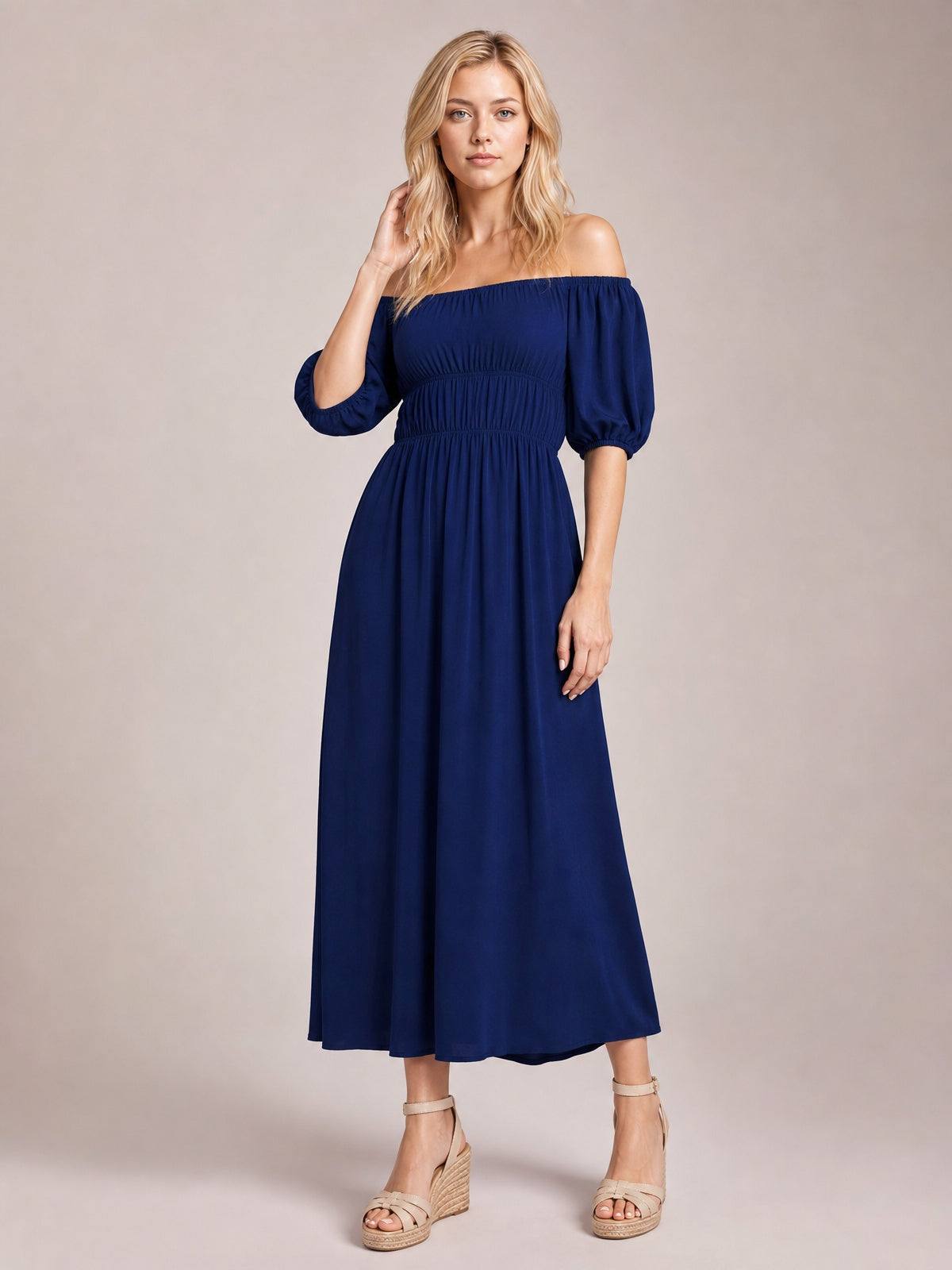 Model poses in a navy blue off-shoulder midi dress with gathered waist, voluminous half-length puff sleeves, and a flowing A-line silhouette.