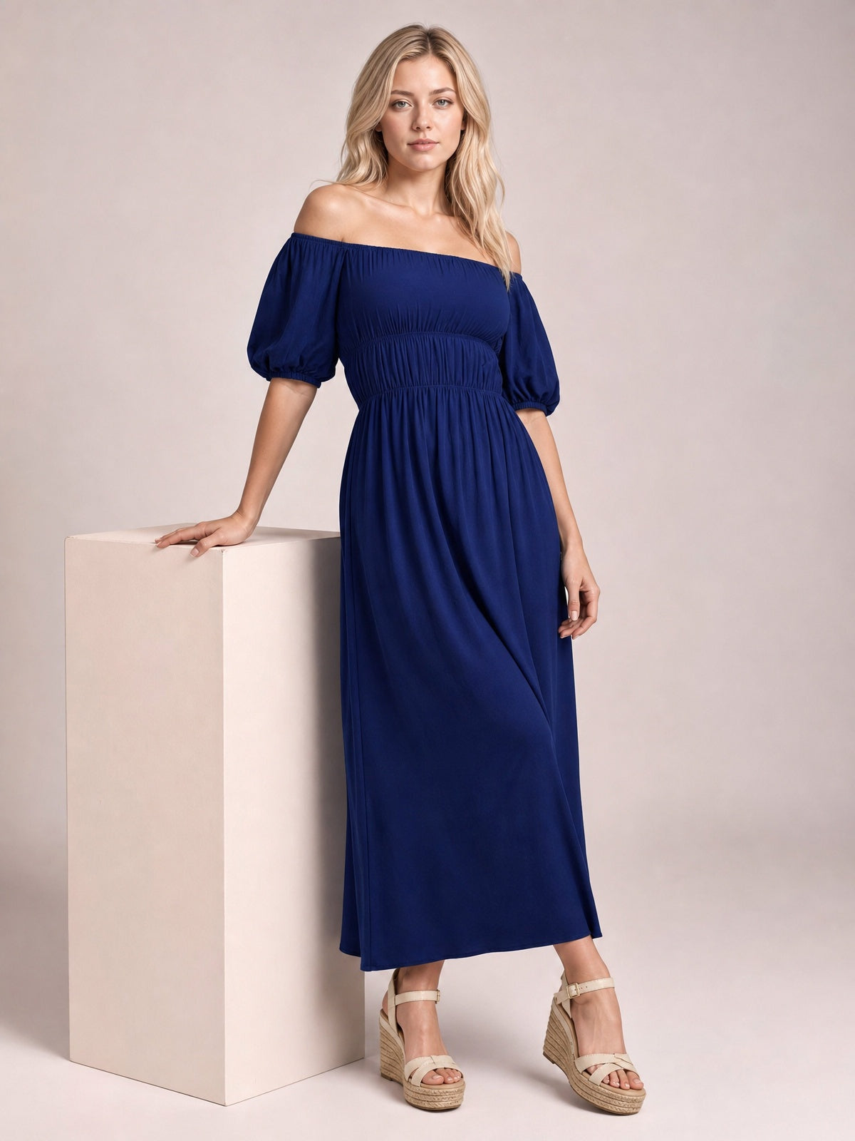 A model poses in a solid navy off-shoulder midi dress with gathered waist, voluminous half-length puff sleeves, and a flowing A-line skirt.