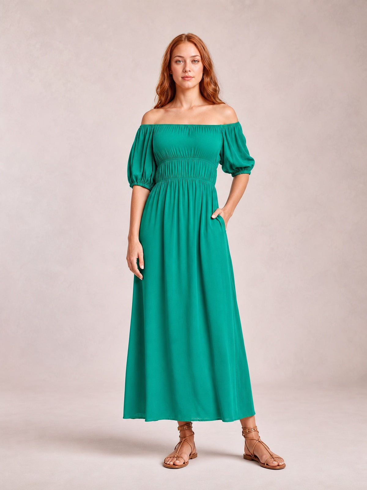 Model in a teal off-shoulder midi dress with voluminous half-length balloon sleeves, gathered waist, and flowing A-line silhouette, posed with one hand in a pocket.