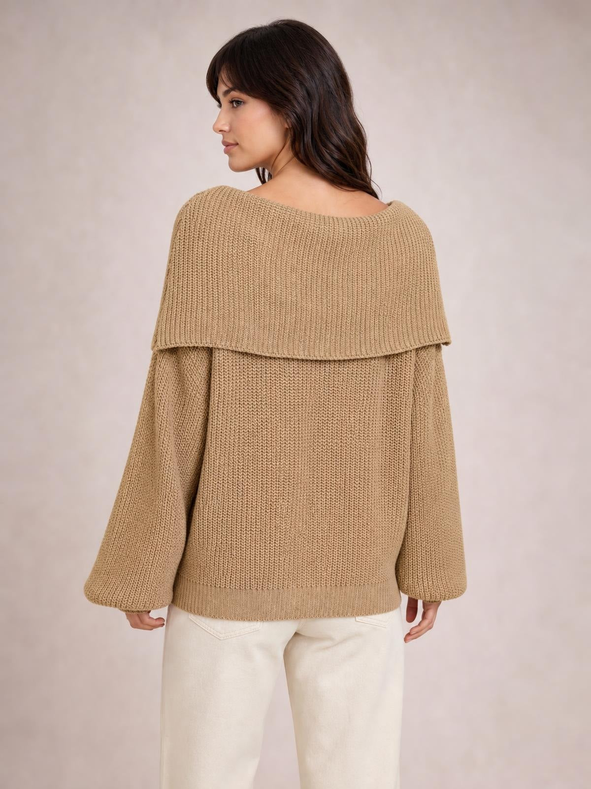 Model turned over her shoulder wears a camel off-shoulder long sleeve sweater with an oversized silhouette, ribbed knit, wide neckline, and ribbed hem.