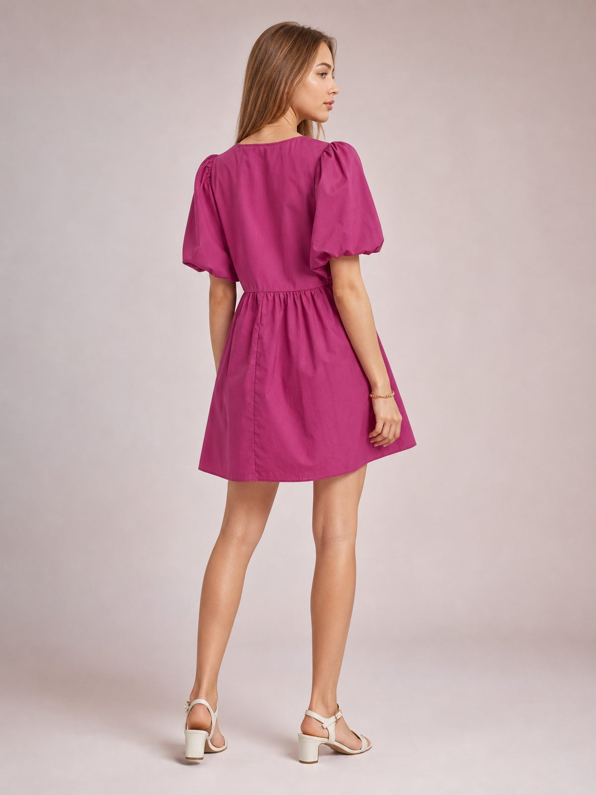 Model shown from the back in a cerise mini dress with voluminous puff sleeves, a softly gathered waist, and a gently flared skirt.