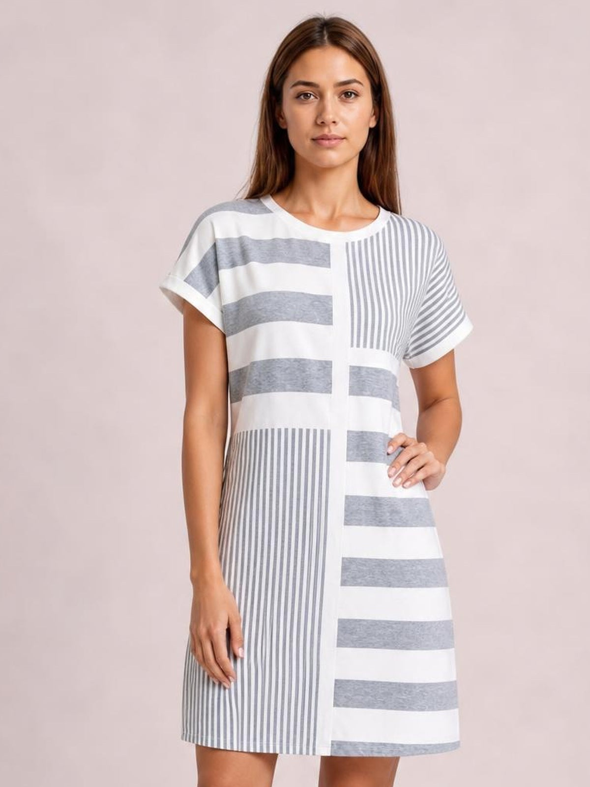 A model poses in a white and gray striped round-neck mini tee dress with short sleeves, mixed horizontal and vertical stripes, and a relaxed straight silhouette.