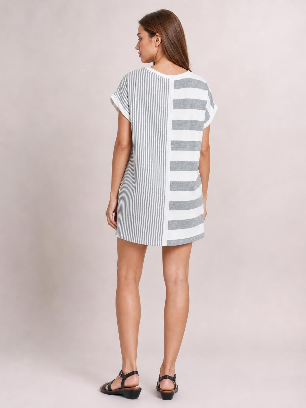 Model shown from behind in a white and gray striped round-neck mini tee dress with short sleeves, a relaxed straight silhouette, and mixed vertical and horizontal stripes.
