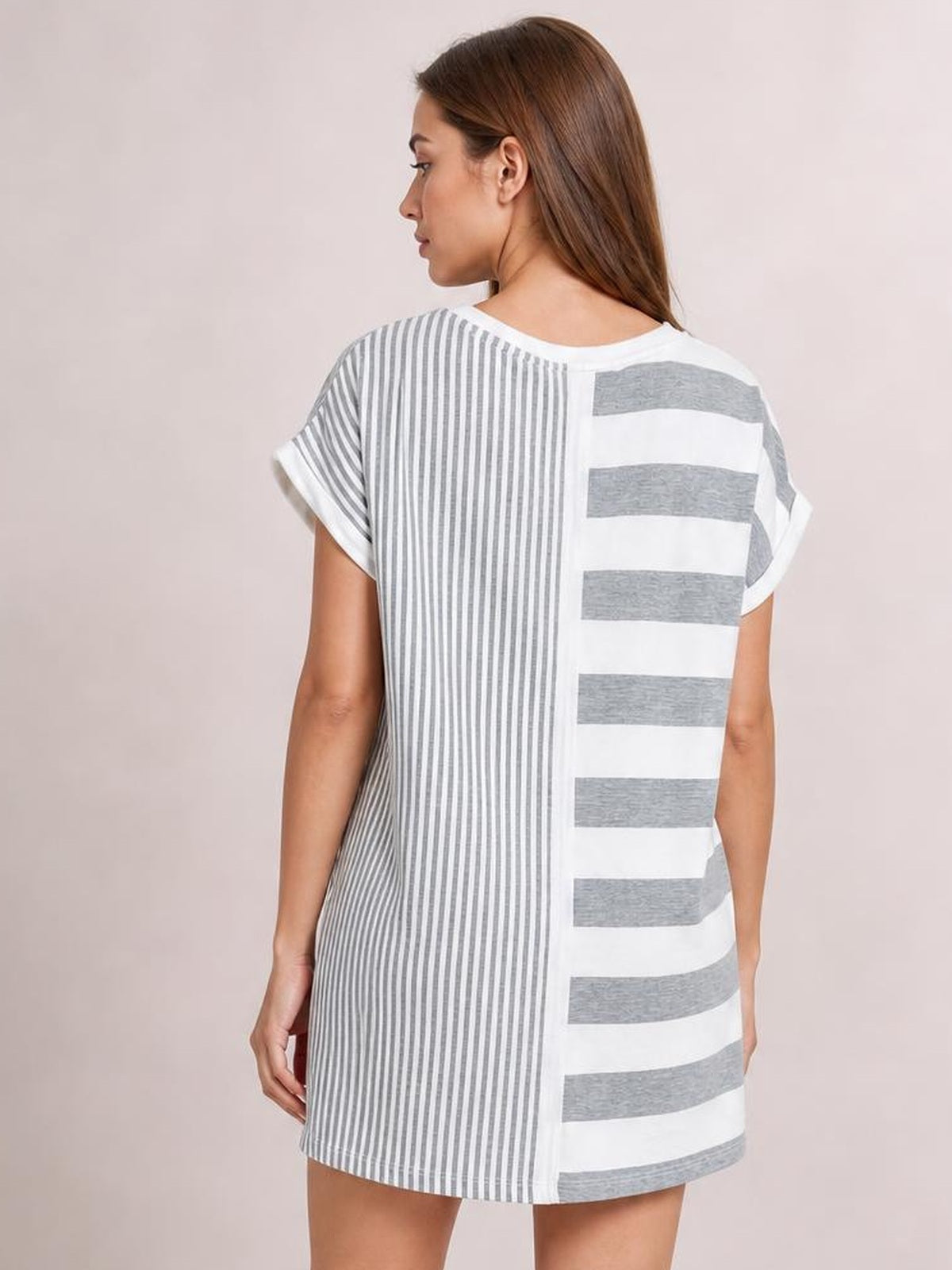 Model looks over her shoulder in a gray and white striped round neck mini tee dress with short sleeves and a relaxed straight silhouette.