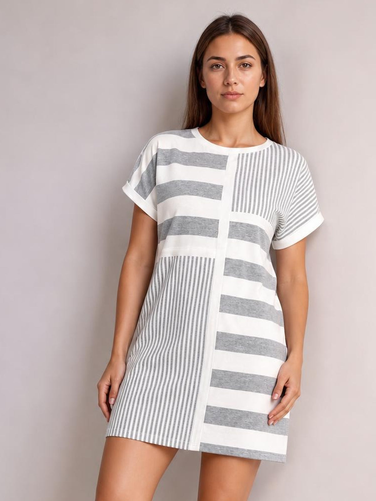 Model wears a gray and white striped round-neck short-sleeve mini tee dress with mixed horizontal and vertical stripes and a relaxed straight silhouette.