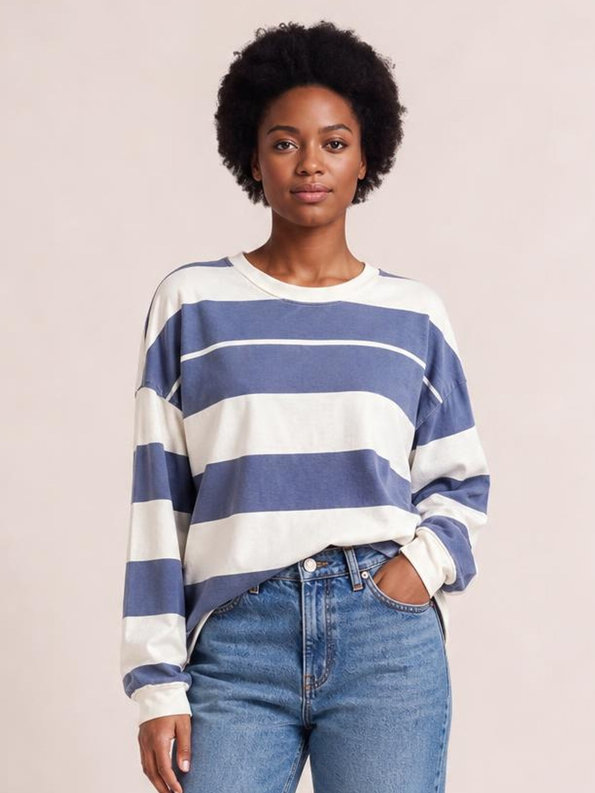 Model wears a relaxed blue and white contrast striped T-shirt with a round neck, long sleeves, exposed seams, and a slightly loose silhouette.