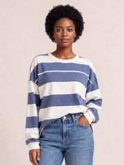 Model wears a relaxed blue and white contrast striped T-shirt with a round neck, long sleeves, exposed seams, and a slightly loose silhouette.