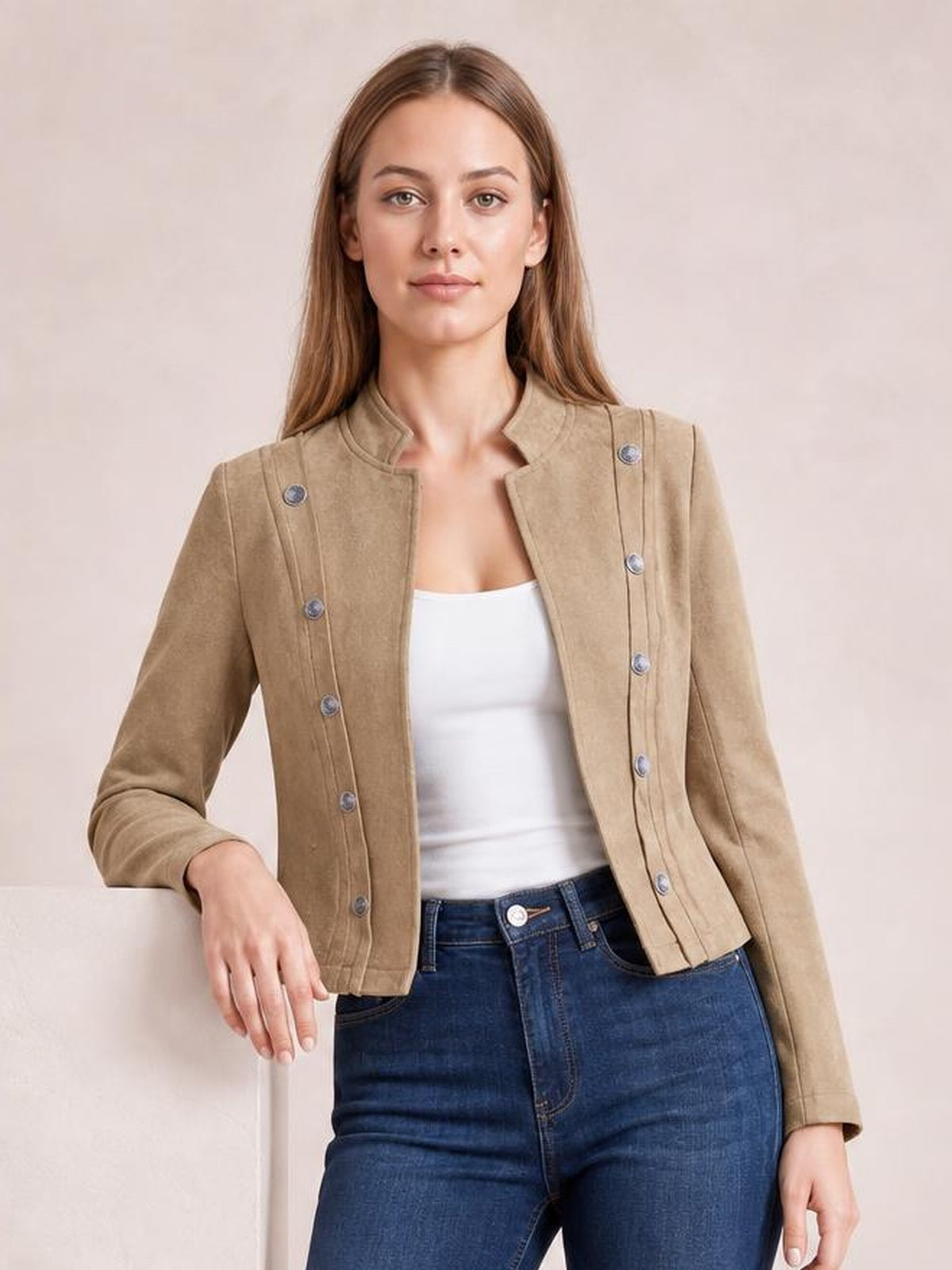 Model wearing a tan open-front cropped jacket with long sleeves, stand collar, structured seams, and multiple decorative buttons over a white top.