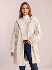 A model wears an ivory fuzzy hooded jacket with long sleeves, an open front, textured construction, and a relaxed longline silhouette.