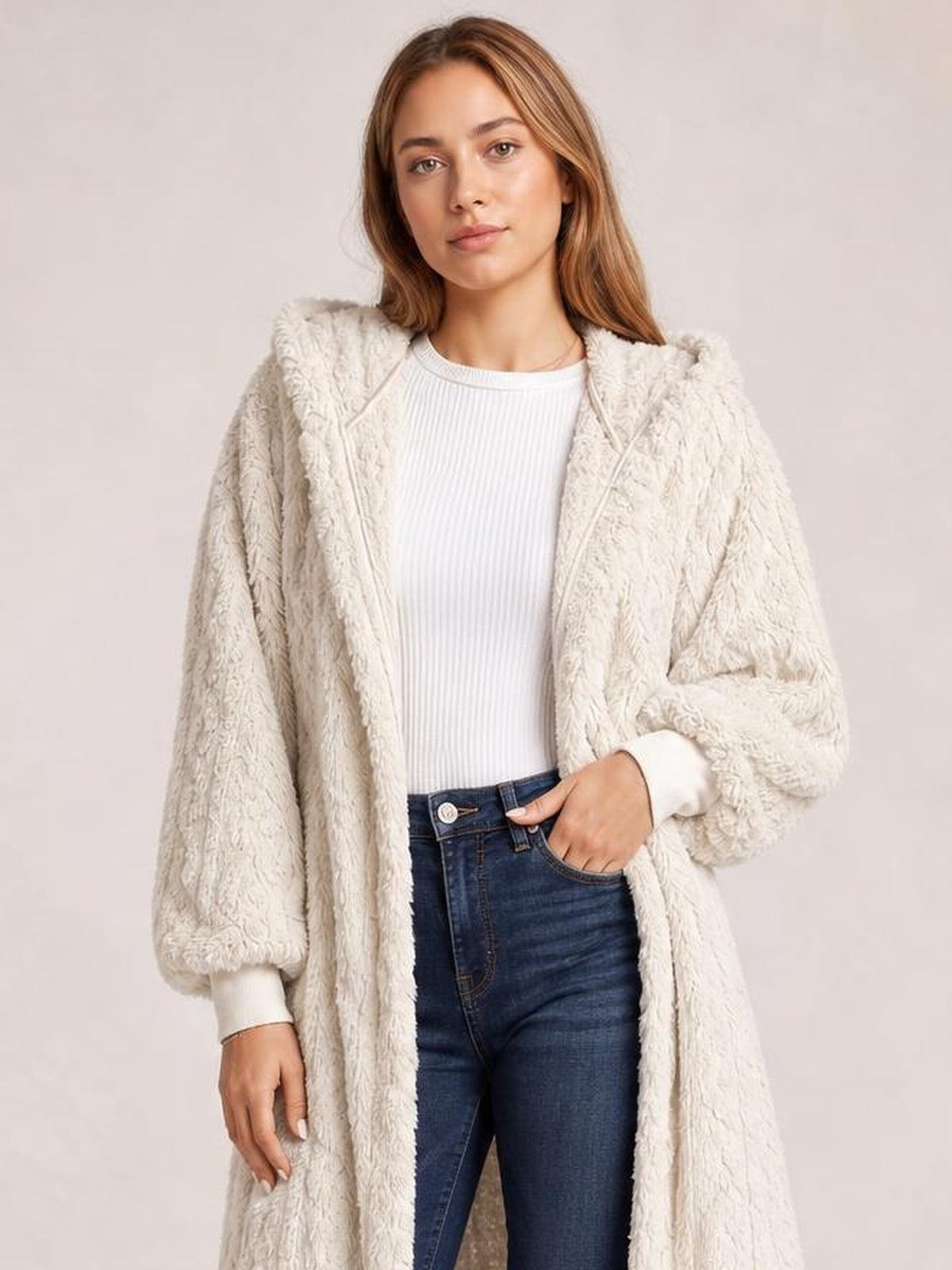 Model wears a cream fuzzy hooded jacket with an open front, long sleeves, ribbed cuffs, and a relaxed longline silhouette.