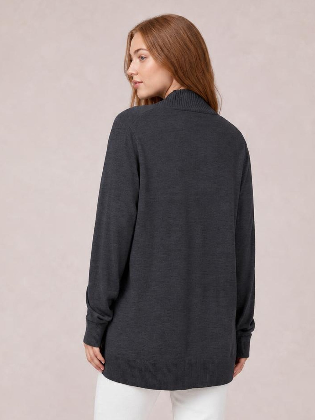 A model looks over her shoulder in a dark gray open-front long-sleeve sweater cardigan with ribbed collar, cuffs, and hem in a relaxed long silhouette.