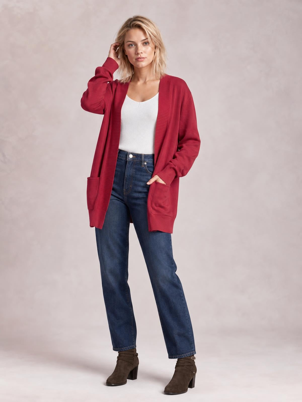 Model wearing a burgundy open front long sleeve sweater cardigan with a relaxed silhouette, ribbed trim, and two front pockets over a white top.