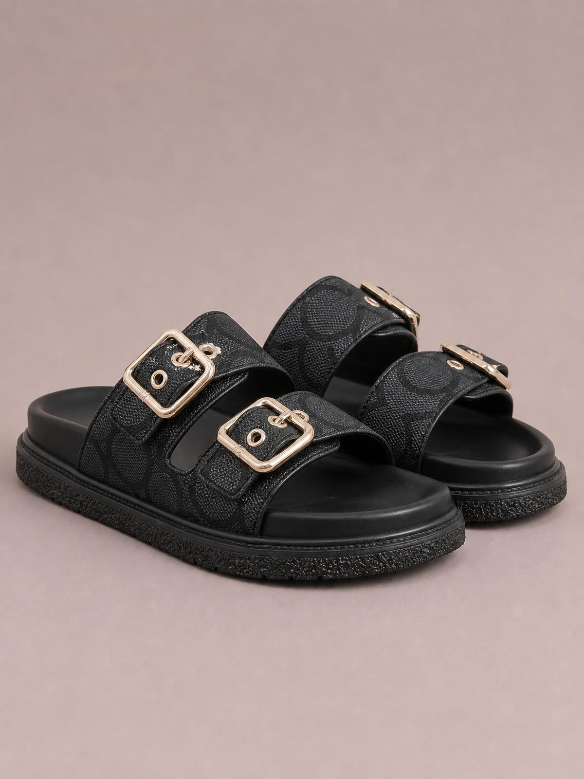 Black open-toe double-buckle flat sandals with textured PU leather straps, gold-tone buckles, cushioned footbeds, and durable rubber soles.