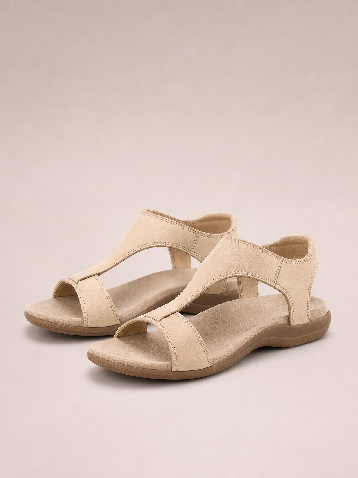 Beige open toe flat sandals with wide front straps, stitched PU leather construction, cushioned footbeds, and textured rubber soles.