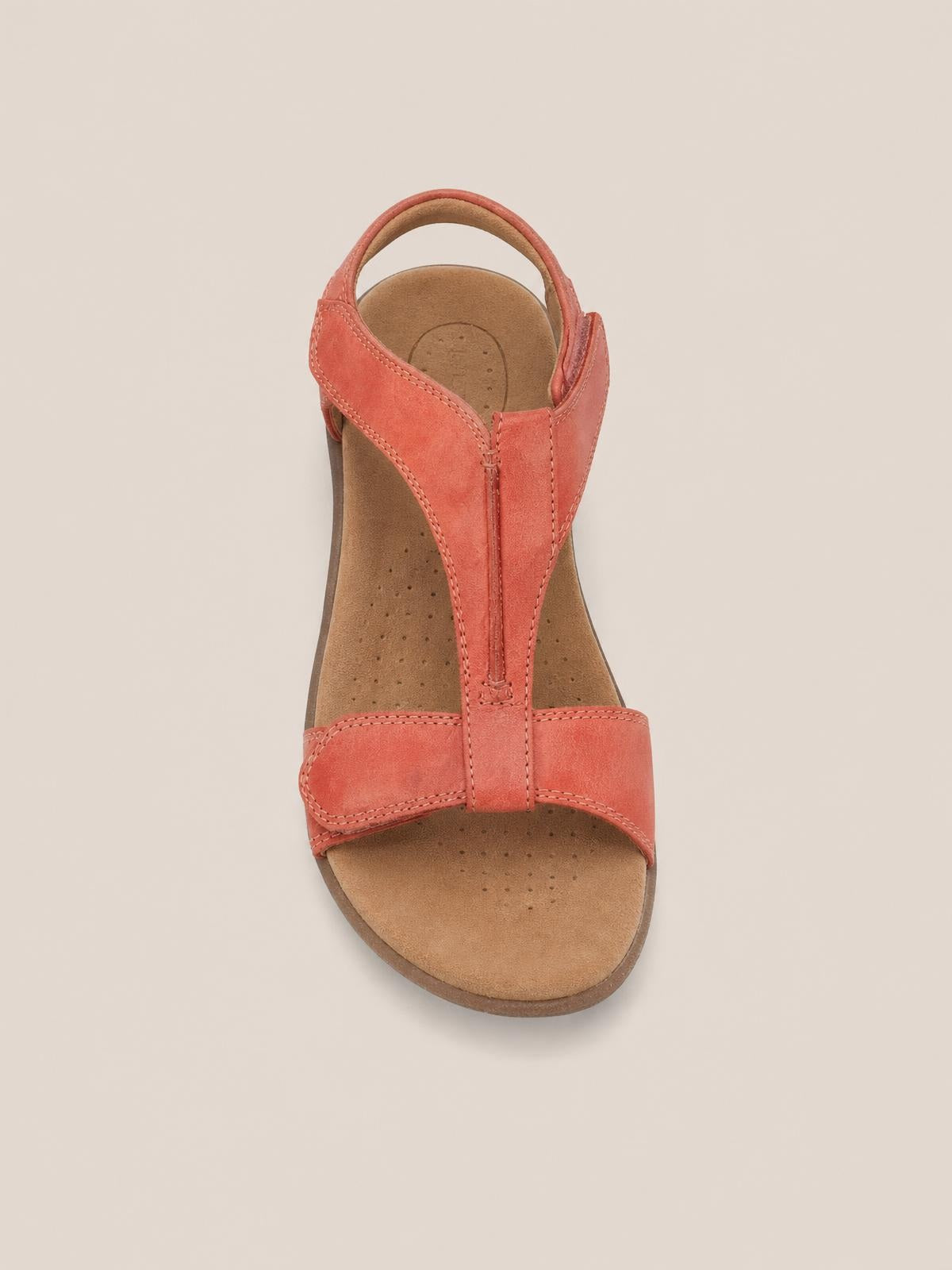 Coral open toe flat sandal with a T-strap design, wide front strap, stitched construction, cushioned footbed, and low rubber sole.