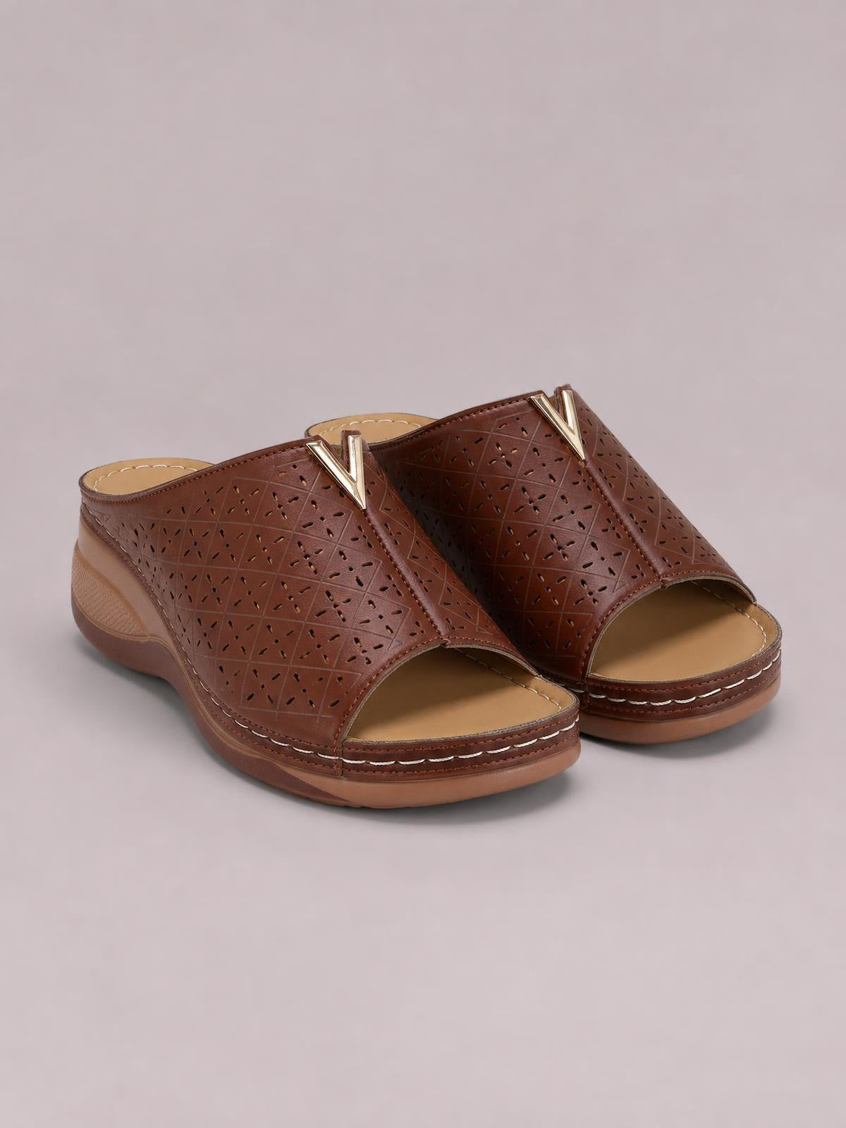 Brown open-toe flat sandals feature perforated PU leather uppers, metallic V accents, cushioned footbeds, and stitched rubber soles.