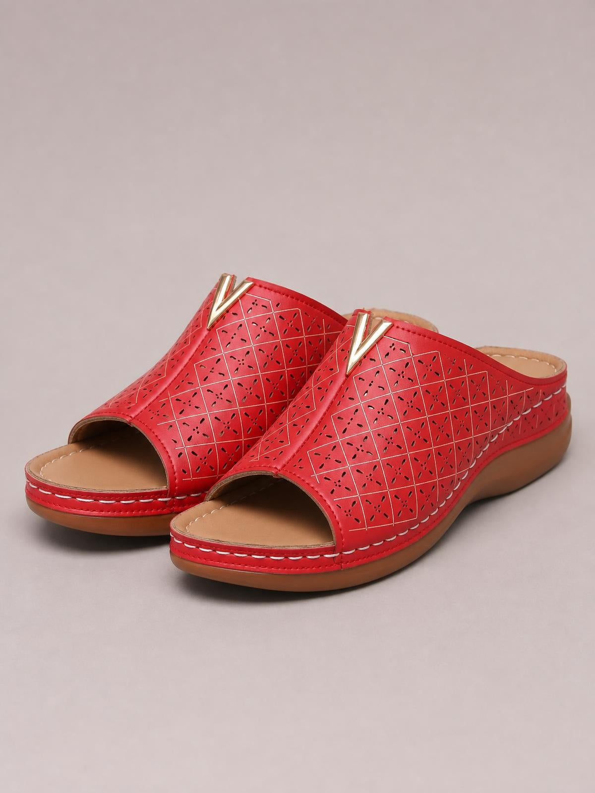 Red open toe flat sandals in PU leather feature perforated geometric uppers, metallic V accents, tan footbeds, stitched edges, and rubber soles.