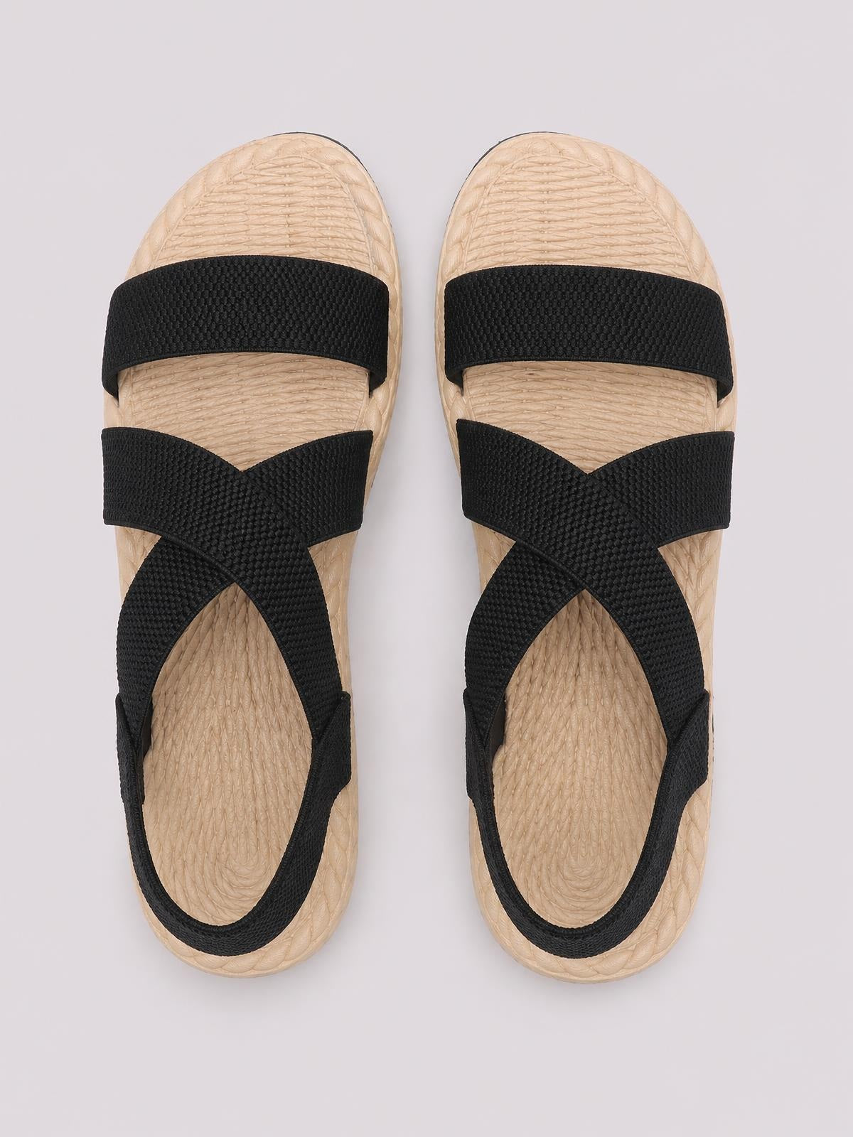 Black open-toe flat sandals feature wide textured straps, a crisscross upper, and beige textured footbeds with a rounded open-toe silhouette.