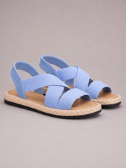 Light blue open toe flat sandals feature wide woven straps, adjustable heel straps, cushioned footbeds, braided midsoles, and black rubber outsoles.