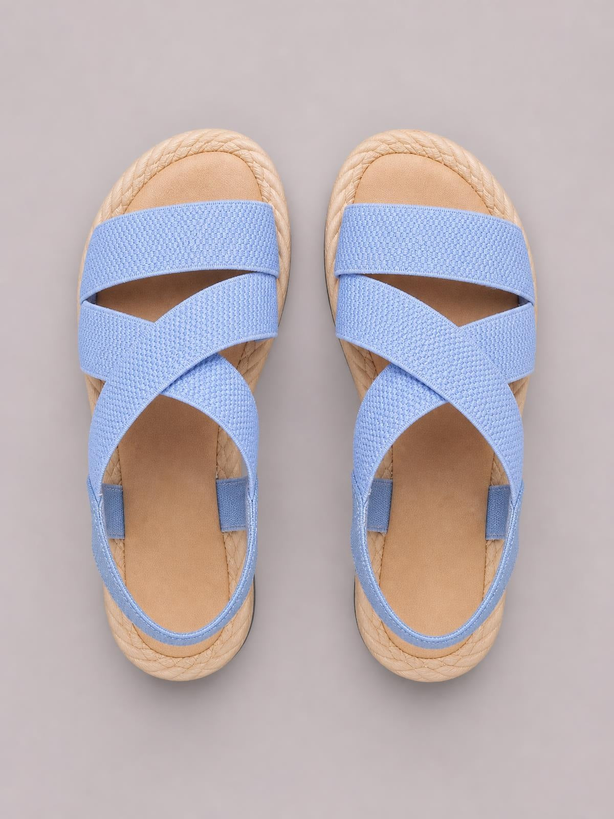 Blue open toe flat sandals feature textured crisscross straps, adjustable ankle straps, and a rounded braided-look sole for a casual silhouette.