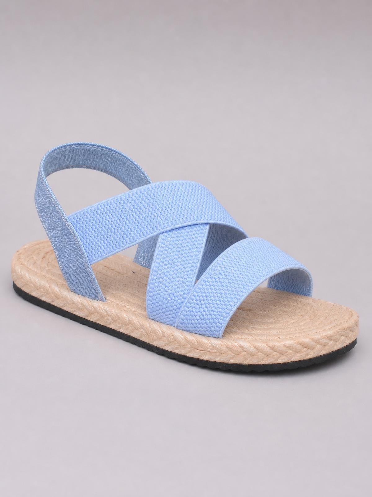 Light blue open toe flat sandals with textured crossover straps, an ankle heel strap, braided natural-tone sole, and contrasting black rubber outsole.