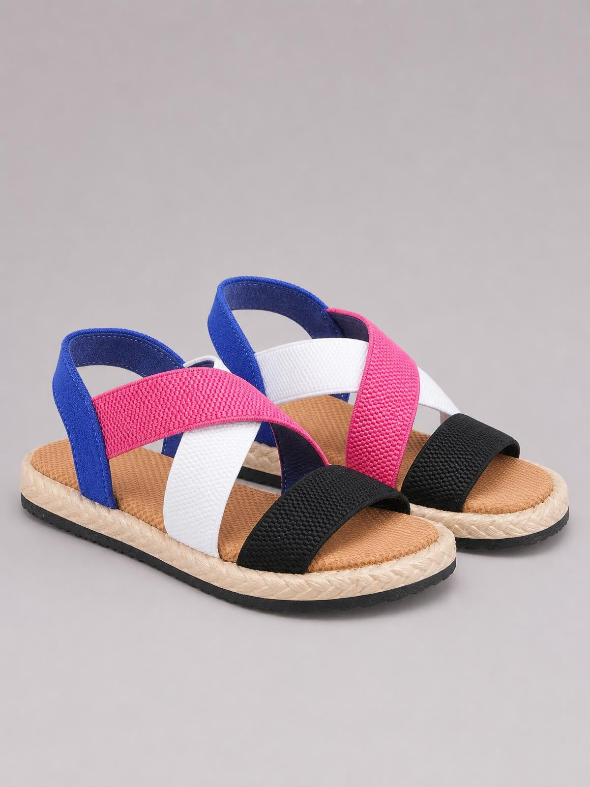 Open toe flat sandals feature colorful blue, pink, white, and black cross straps, woven-textured footbeds, and braided espadrille-style soles with black rubber outsoles.