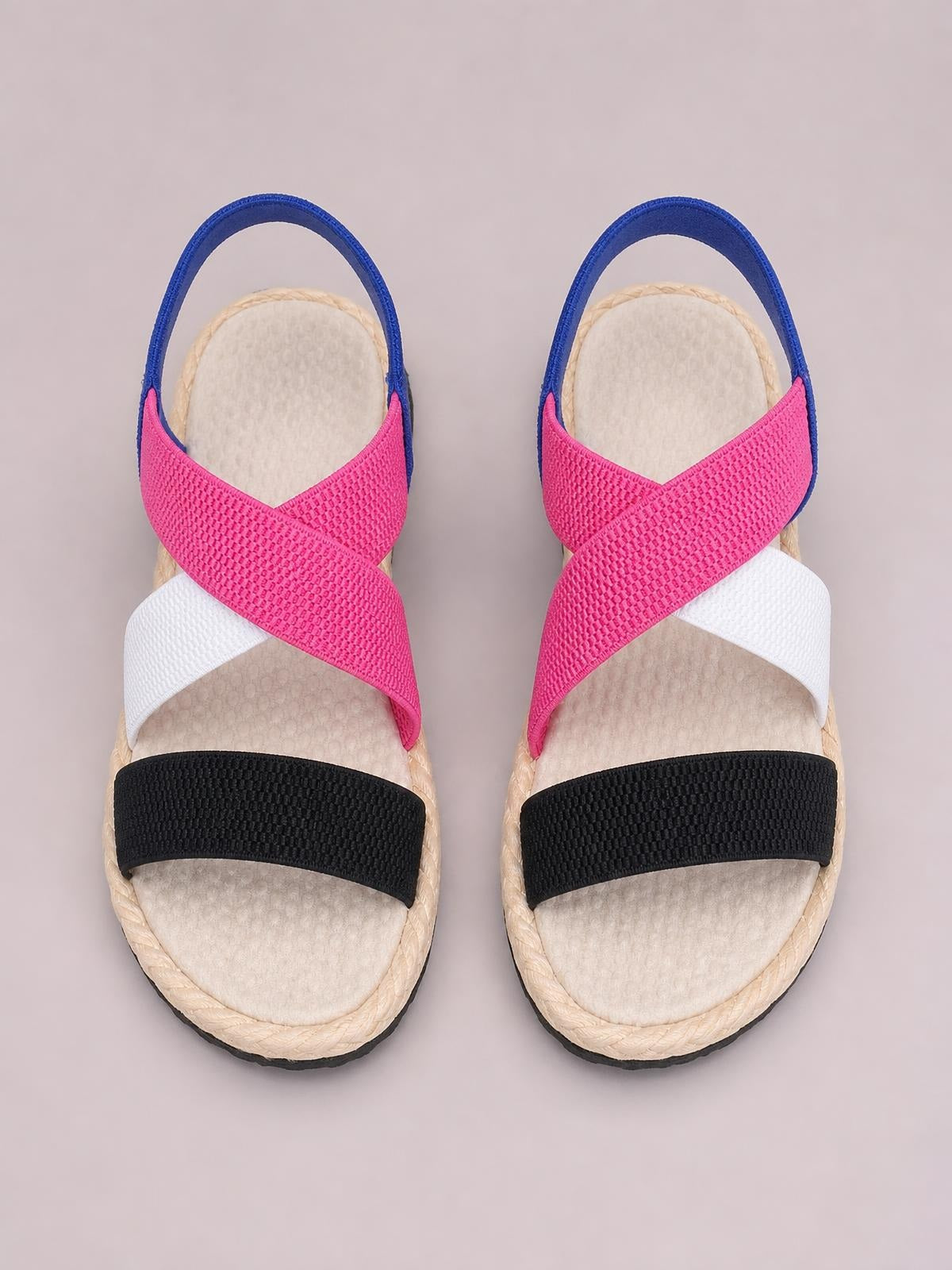Open toe flat sandals with pink, white, and black textured crossover straps, blue heel straps, cushioned footbeds, and braided trim.