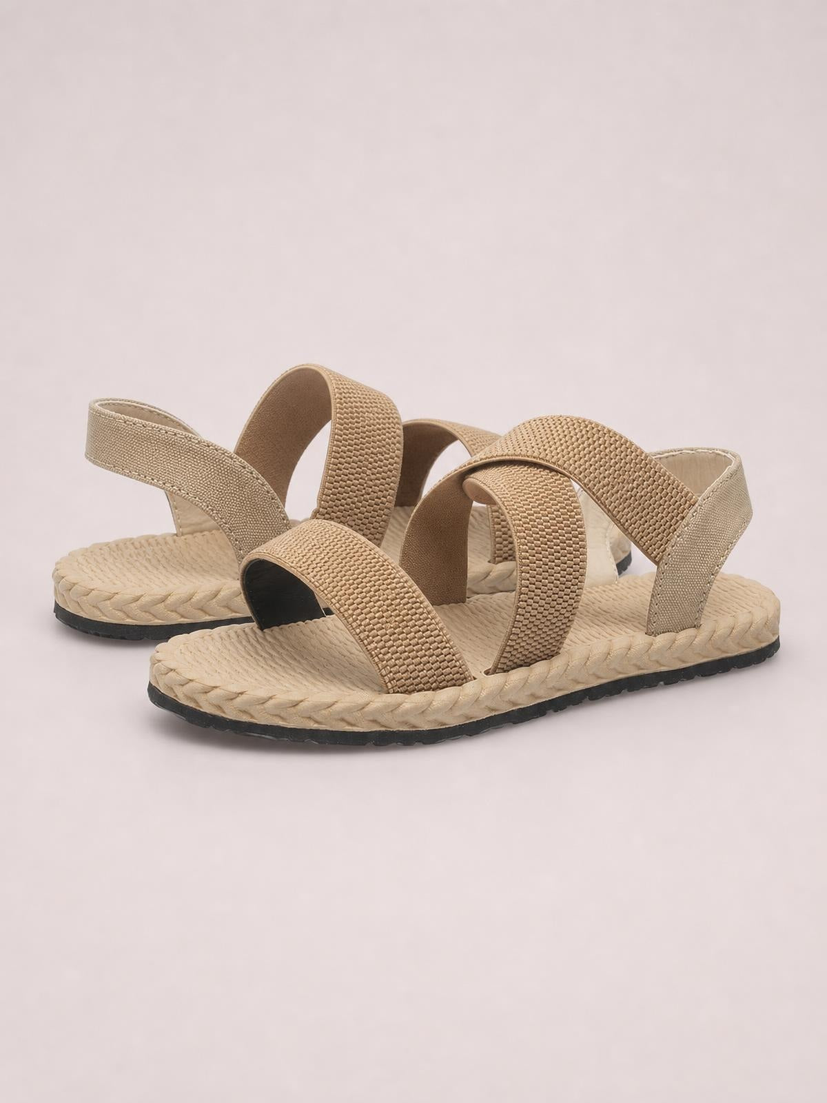 Beige open toe flat sandals with wide woven crossover straps, supportive heel bands, textured braided soles, and durable black rubber outsoles.