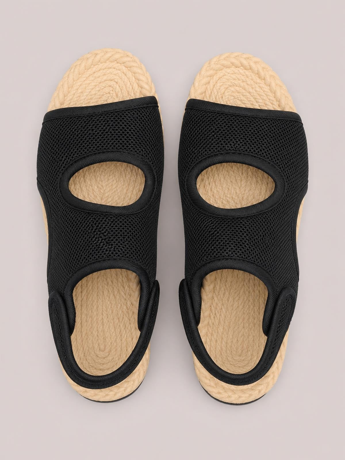 Pair of black open toe mesh flat sandals with breathable mesh panels, oval cutouts, supportive side straps, and textured woven-look soles.