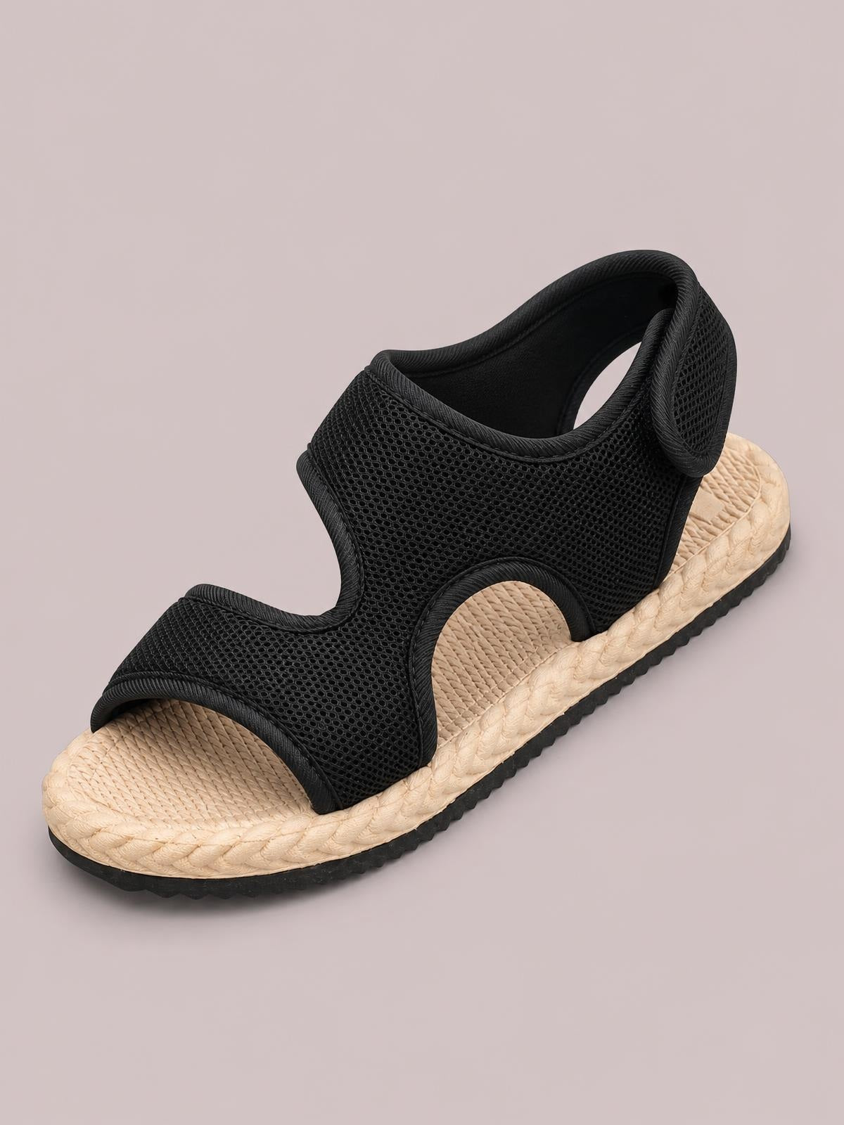 A black open toe mesh flat sandal features breathable cutout construction, a woven beige footbed and braided midsole over a black rubber outsole.