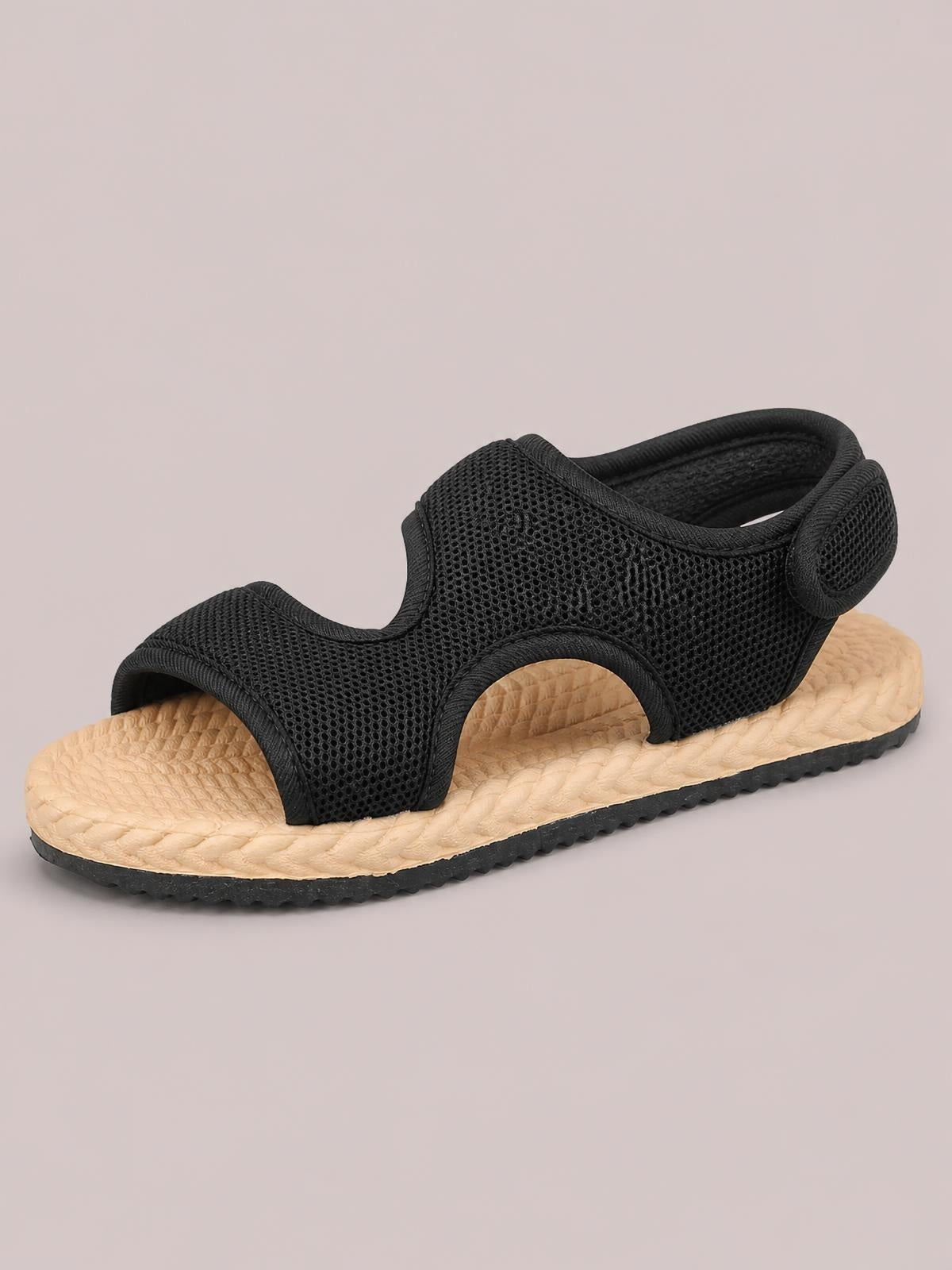 Black open-toe mesh flat sandal with cutout construction, padded straps, textured tan footbed, and a black rubber outsole.