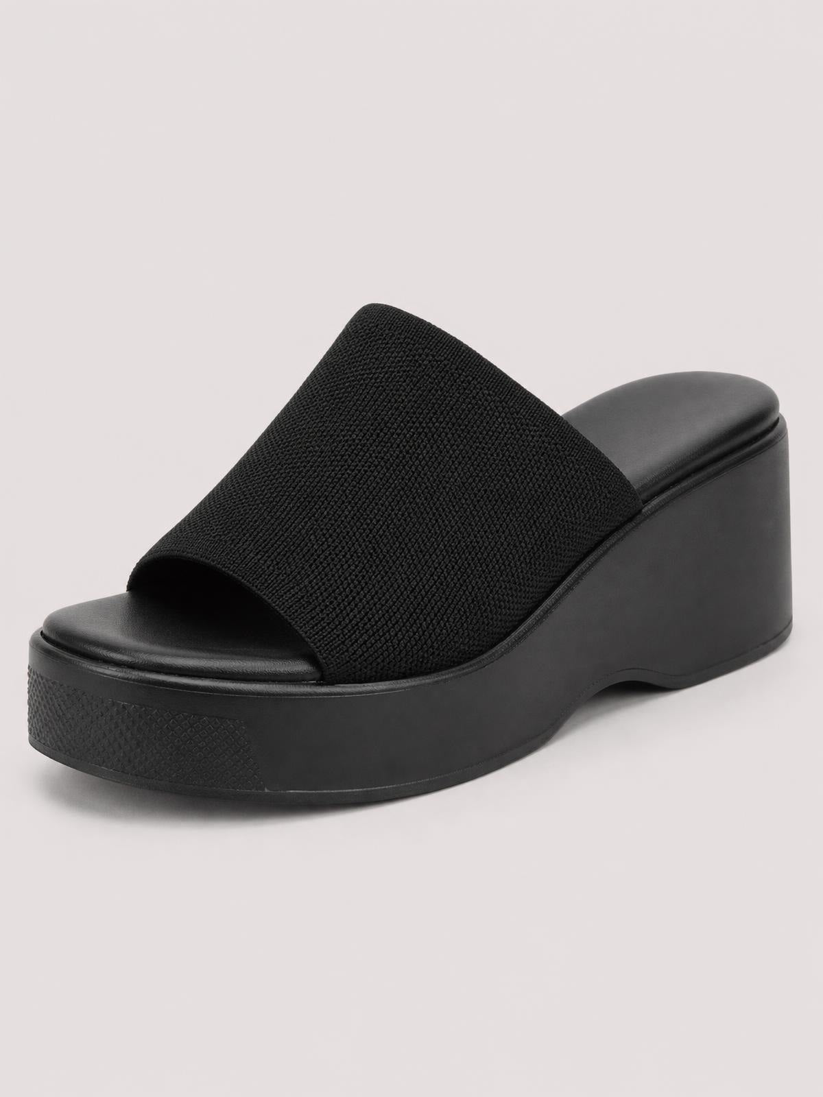 Black open-toe platform cloth sandal with a wide textured upper, cushioned footbed, and substantial rubber wedge sole for a bold slip-on silhouette.