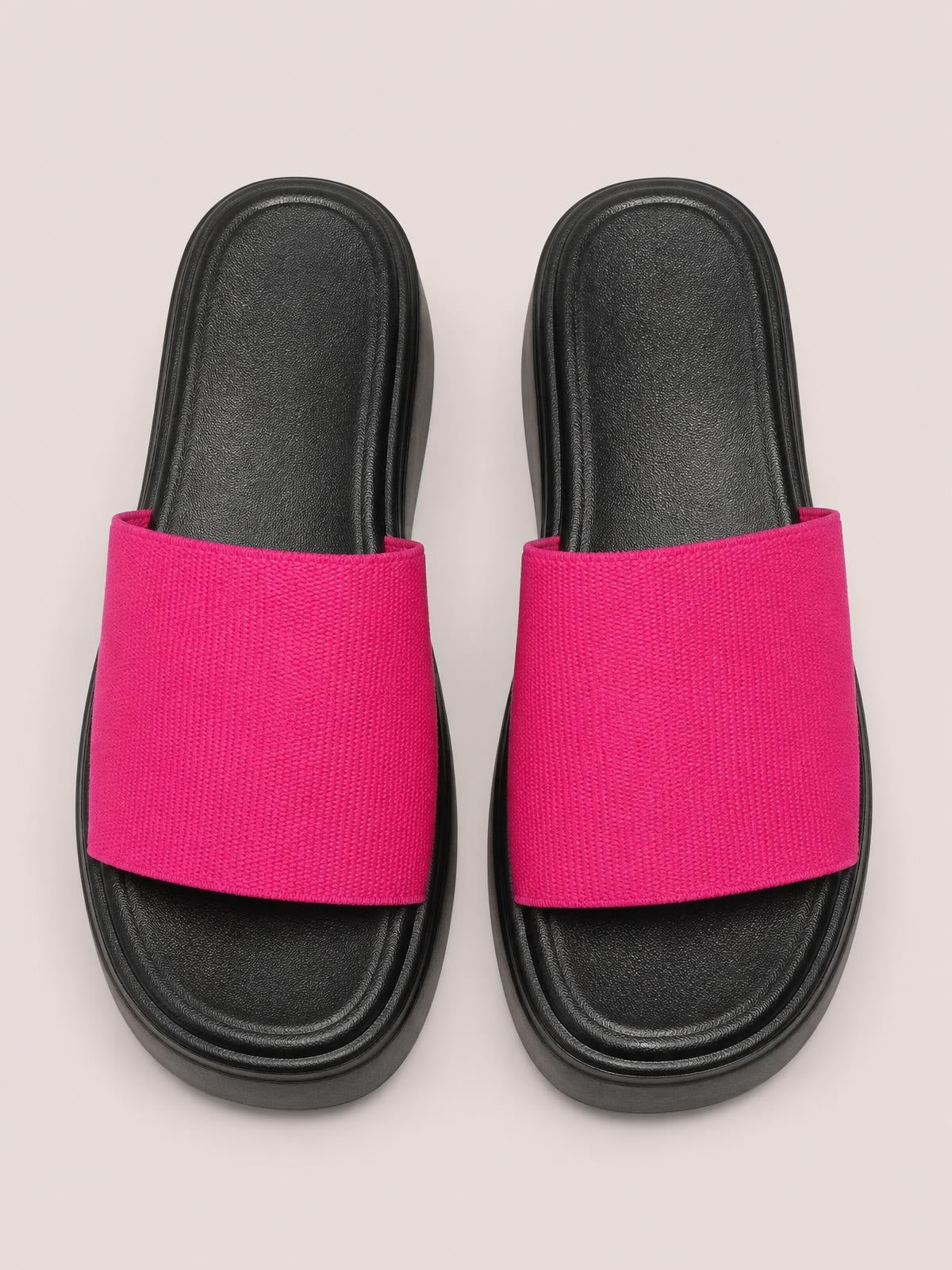 Bright pink open-toe cloth sandals with wide slip-on straps, black cushioned footbeds, and thick flat platform rubber soles.