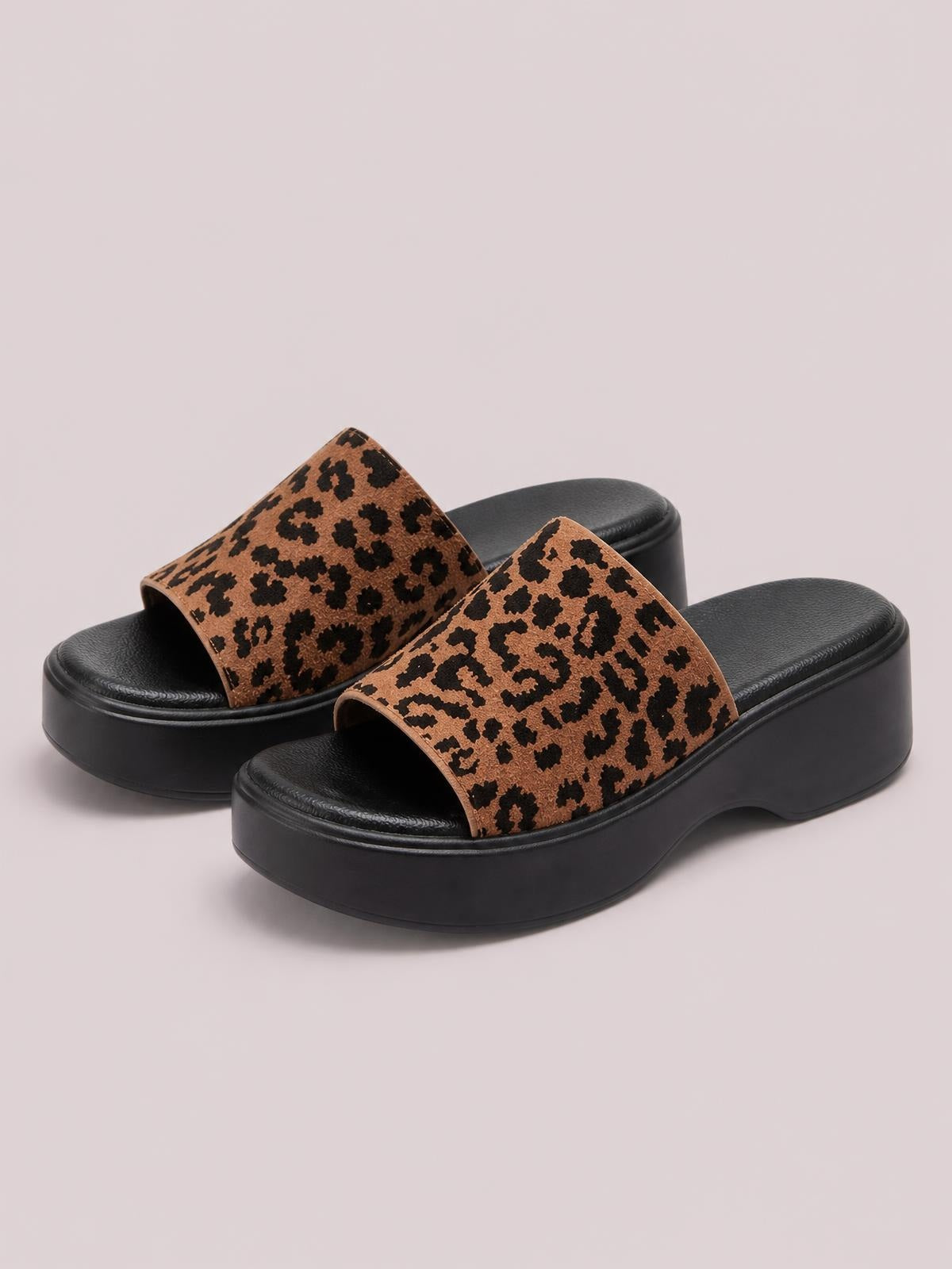 Leopard-print cloth sandals feature wide open-toe straps and chunky black rubber platform soles with a flat, supportive silhouette.