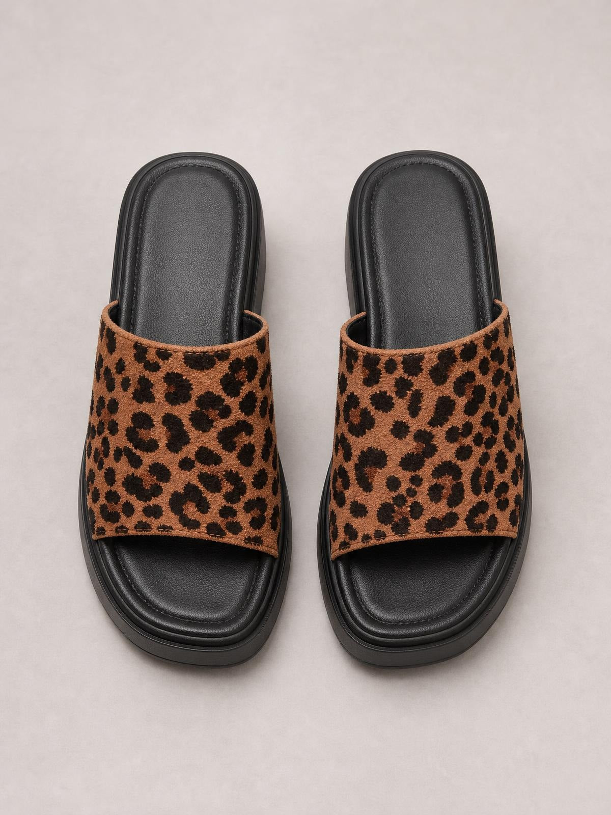Brown leopard-print cloth open-toe platform sandals feature wide slip-on straps, black cushioned footbeds, and thick rubber flat soles.