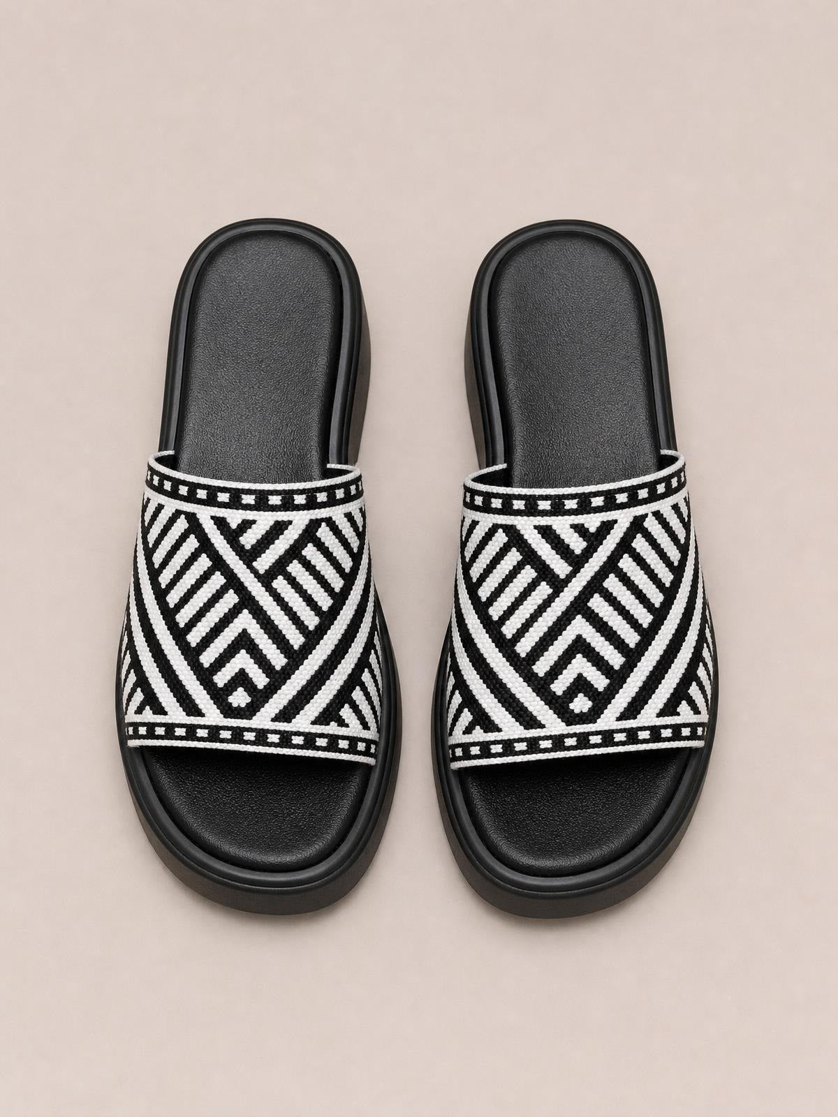 Black-and-white open-toe platform cloth sandals feature wide geometric-patterned straps, cushioned footbeds, and thick rubber soles.