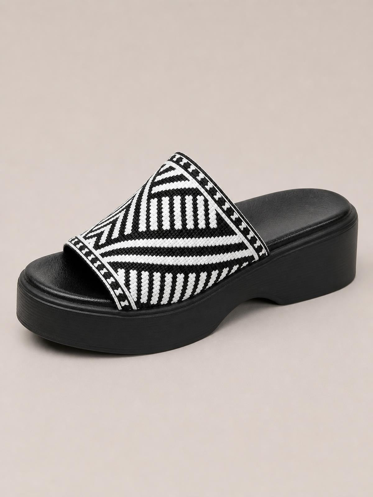 Black-and-white open toe platform cloth sandal with a bold geometric woven upper, wide slip-on strap, and chunky black rubber sole.