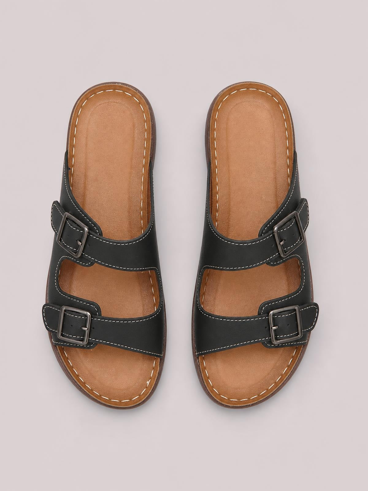 Black open toe platform sandals feature two adjustable buckled straps, contrast stitching, tan cushioned footbeds, and sturdy flat rubber soles.