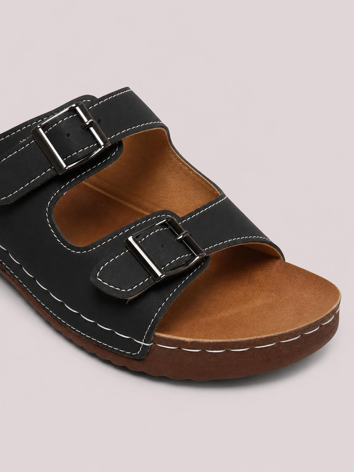 Black open toe platform sandals feature two adjustable buckle straps, contrast stitching, tan footbeds, and thick brown rubber soles.