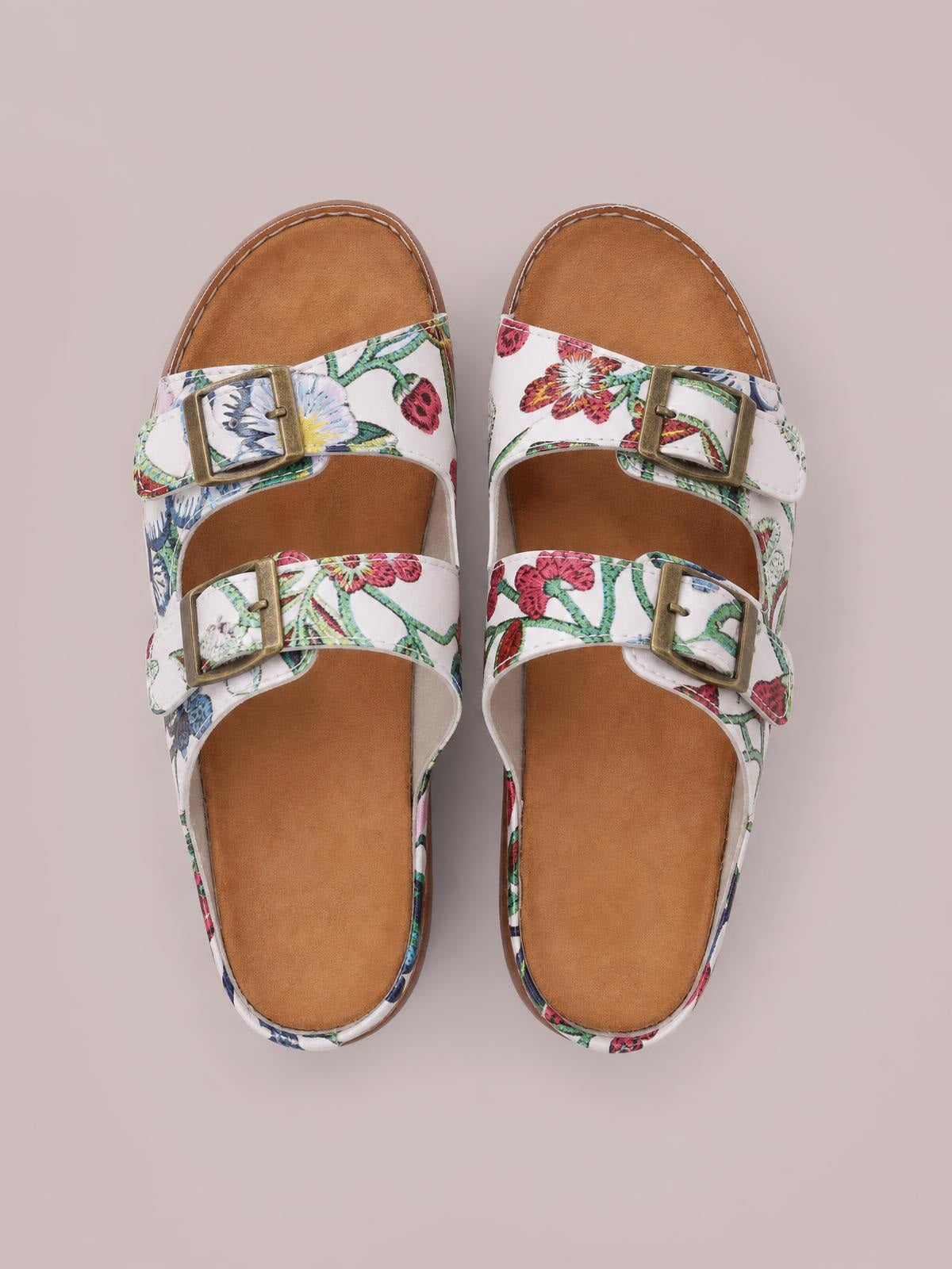 White floral open-toe platform sandals feature two adjustable buckled straps, cushioned footbeds, and flat rubber soles for comfortable everyday wear.