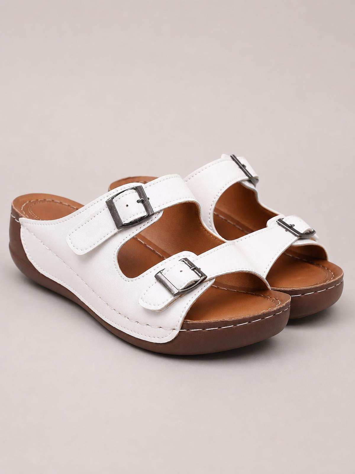 White open toe platform sandals with two adjustable buckle straps, cushioned brown footbeds, stitched PU leather uppers, and flat rubber soles.