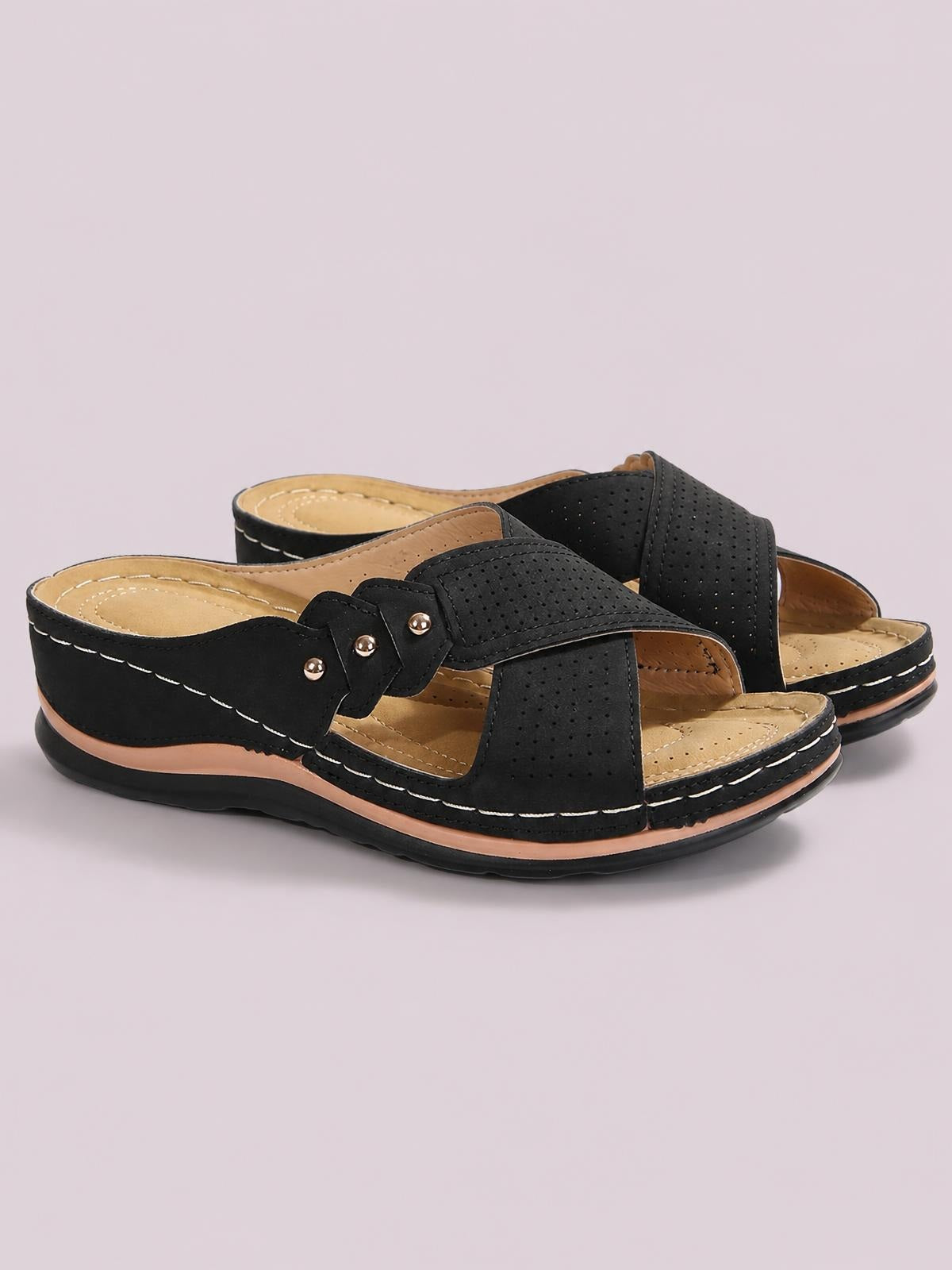 Black open-toe platform sandals in PU leather feature perforated crossed straps, stud accents, tan cushioned footbeds, contrast stitching, and textured rubber soles.