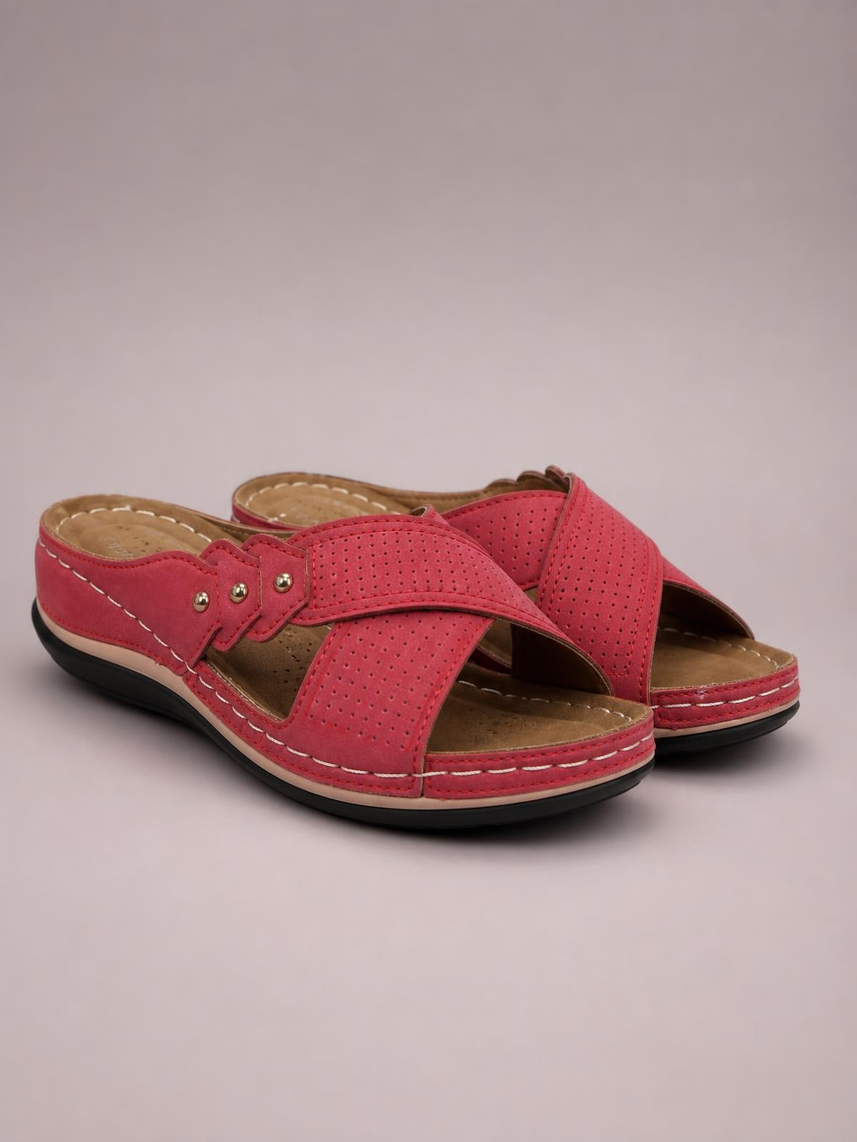 Red open-toe platform sandals with perforated crossover straps, decorative studs, contrast stitching, cushioned footbeds, and black rubber soles.