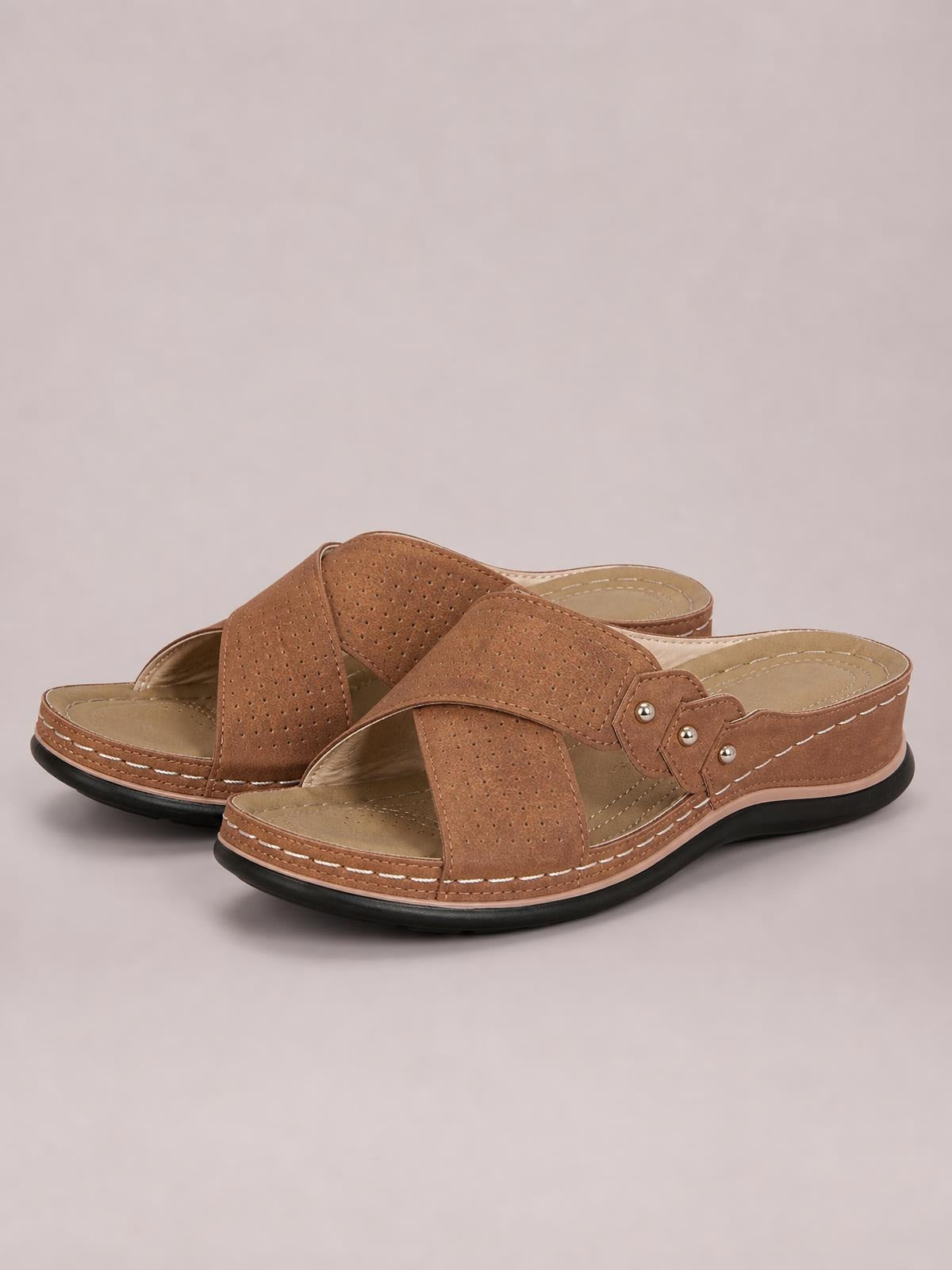 Brown open toe platform sandals feature perforated crossover straps, decorative studs, contrast stitching, cushioned footbeds, and thick black rubber soles.